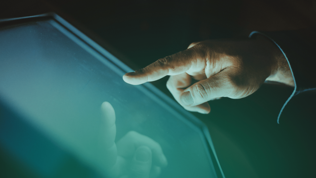 Dedo de uma pessoa tocando a tela de um dispositivo digital, simbolizando validação de dados e checagem automatizada em processos de recrutamento.