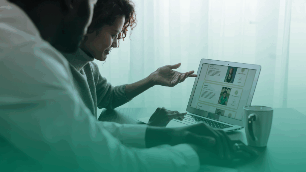Funcionários de RH aprendendo a usar uma plataforma ATS; uma mulher de cabelos cacheados e um homem concentrados em um notebook com uma xícara ao lado.