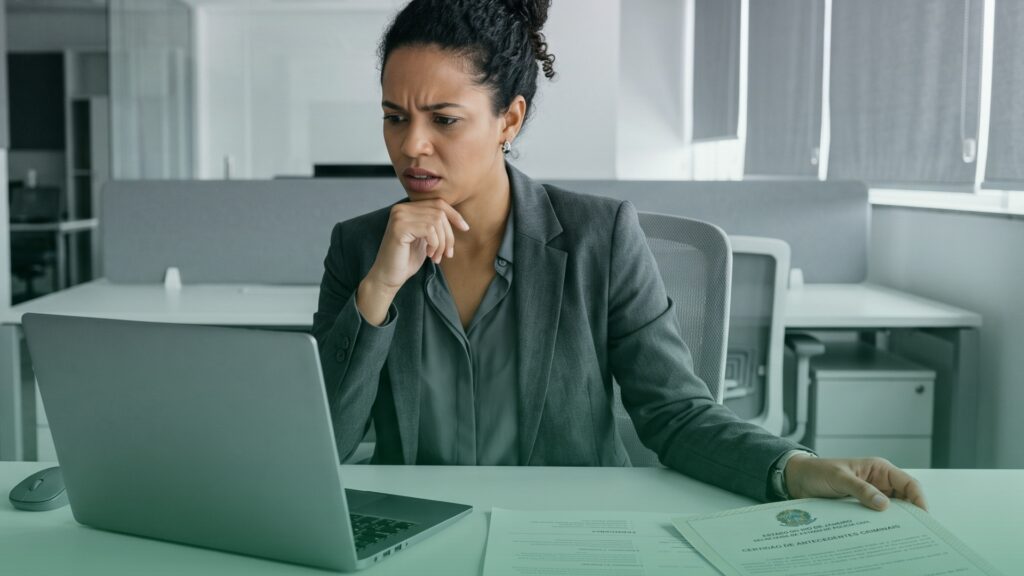 Profissional de RH, sentada em sua mesa em escritório, analisa as mudanças ocorridas nos últimos 9 (nove) anos no mercado de verificações de antecedentes para aplicar o background check e garantir mais segurança na empresa.